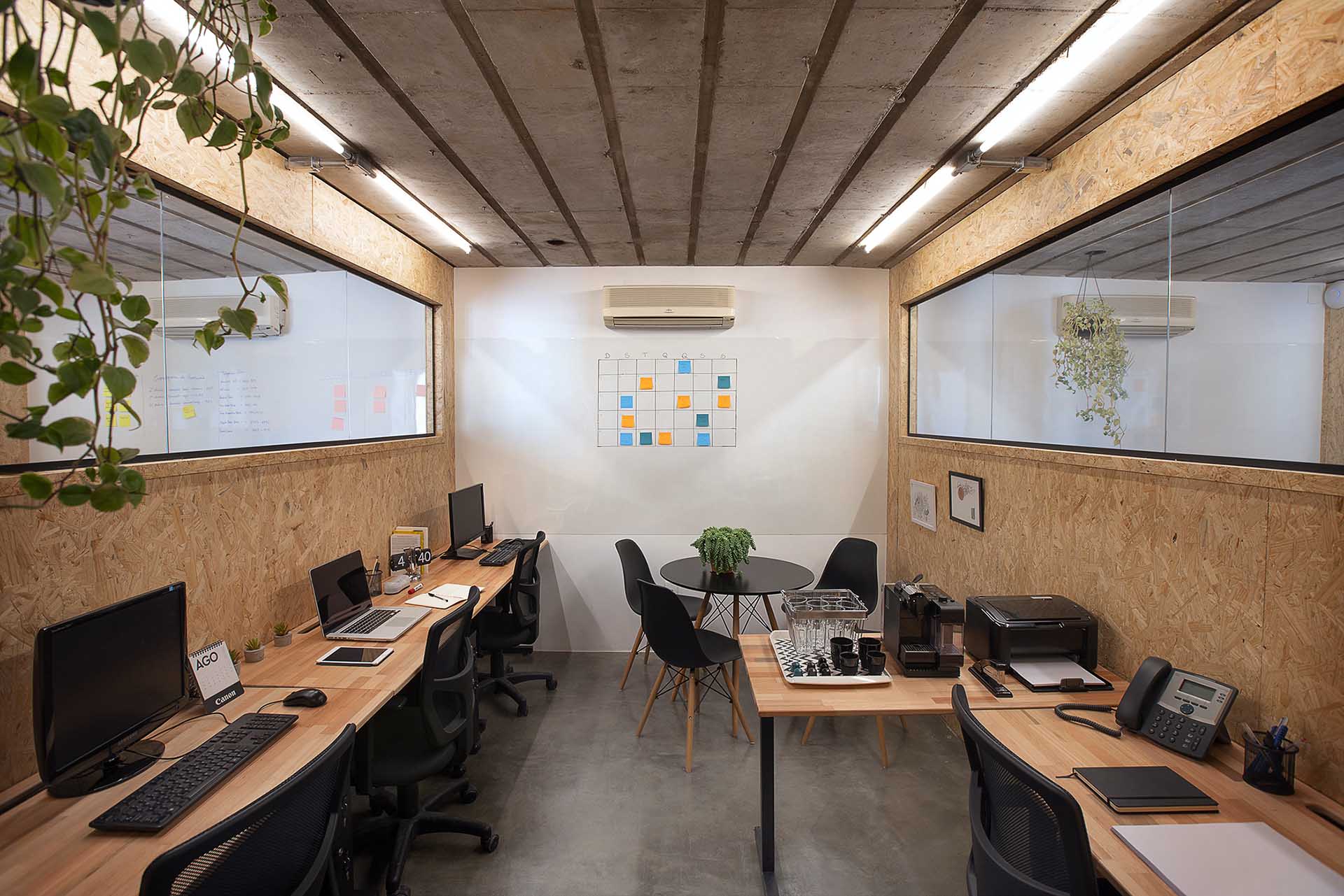 Sala privativa na Berrini para até 6 pessoas com computadores, mesas flexíveis e uma planta pendurada